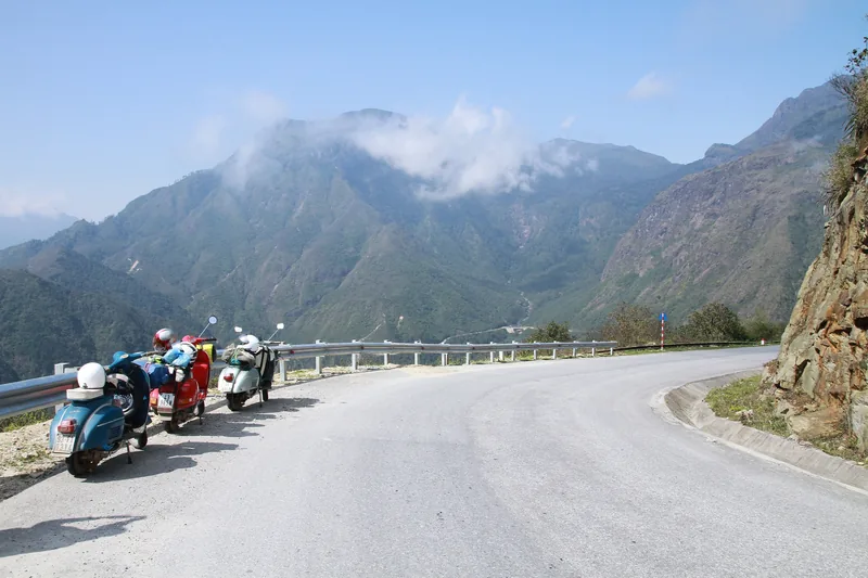 Những chiếc xe Vespa đỗ bên con đường đèo uốn lượn nhìn ra núi mù sương gần Sa Pa, Lào Cai.