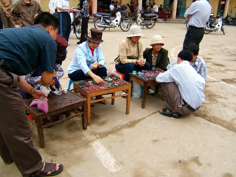 Người bán ngồi trên ghế thấp bày bán đá quý và hạt cườm tại chợ đường phố ở Lục Yên, Yên Bái.