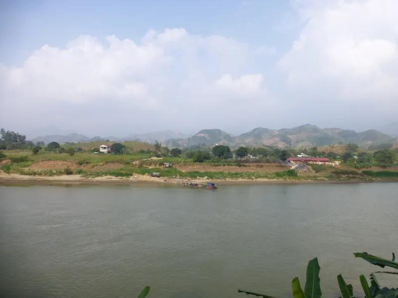 Dòng sông rộng chảy qua một làng quê và những dãy đồi xa gần huyện Văn Yên trên đường DT163.